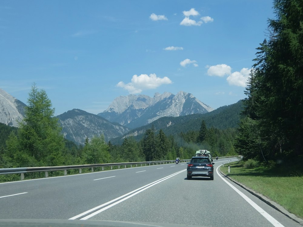 Auto auf einer Bundesstraße vor Alpengipfeln